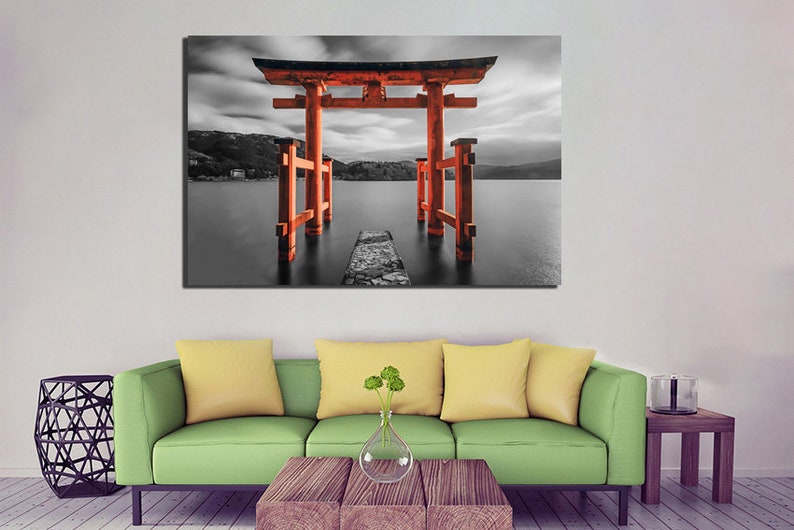 May include: A red Japanese Torii gate stands in a black and white landscape, with a stone path leading to it. The gate is reflected in the water, creating a symmetrical image.