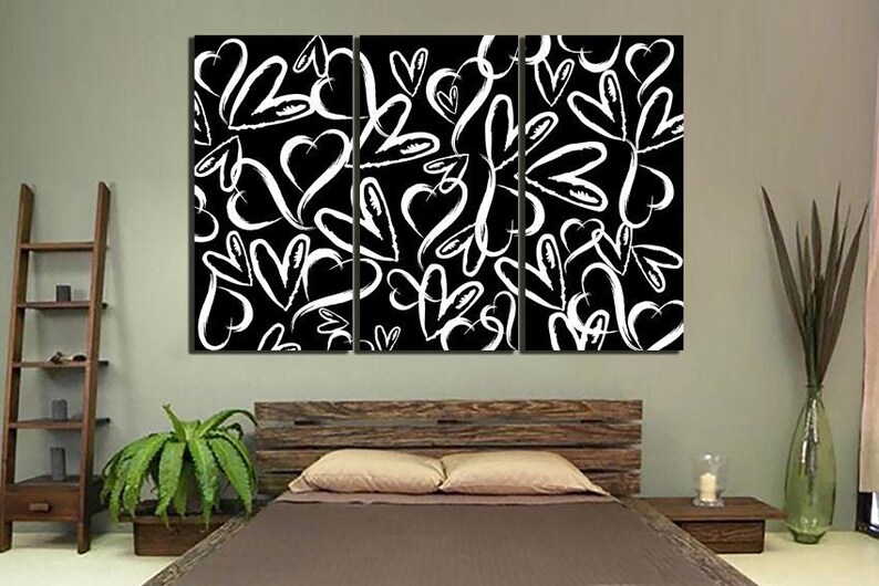 Puede incluir: Una impresi&oacute;n de arte de pared de lienzo en blanco y negro con un patr&oacute;n repetitivo de corazones blancos sobre un fondo negro. La impresi&oacute;n est&aacute; dividida en tres paneles.