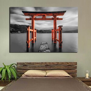 May include: A black and white photograph of a red Japanese Torii gate standing in a body of water. The gate is a traditional Japanese structure that is often found at the entrance to a shrine.