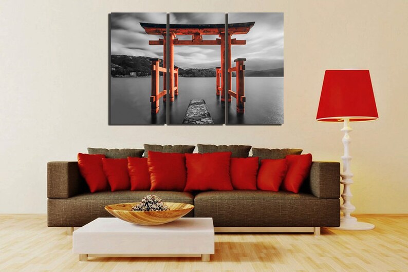 May include: A three-panel canvas print featuring a red Japanese torii gate, a traditional gateway to Shinto shrines, standing in a body of water. The gate is surrounded by a black and white landscape, creating a striking contrast.