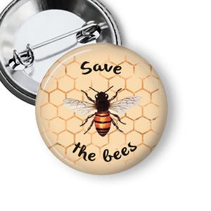 May include: A round button pin with a bee illustration and the text "Save the bees." The bee is black and orange with white wings, set against a honeycomb pattern. The pin has a silver metal backing.