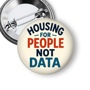 May include: A round pin-back button with a cream-colored background featuring the text HOUSING FOR PEOPLE NOT DATA in dark blue and red block lettering. The back of the button is metallic silver with a standard pin mechanism for attachment.
