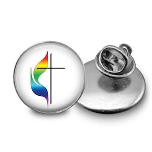 May include: A round, silver-colored pin with a white background. The pin features a stylized cross with a flame design in rainbow colors. The pin is shown next to its back piece, which has a pin clasp.
