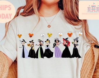 May include: A white t-shirt with a graphic of Disney princesses dressed as witches holding Mickey Mouse balloons. The princesses are dressed in their signature colors and have witch hats on. The balloons are orange, green, purple, and white.