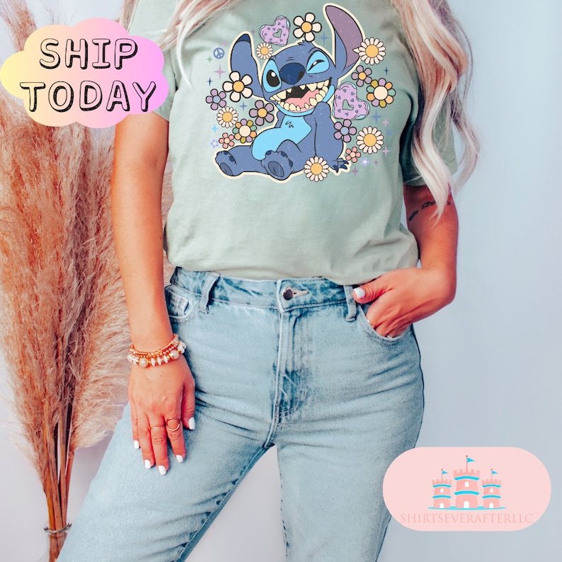 May include: A light green t-shirt with a blue cartoon character surrounded by flowers and hearts. The character is smiling and has a peace sign on its head. The text "SHIP TODAY" is in a white cloud in the top left corner of the image.
