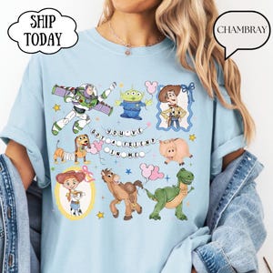 Puede incluir: Una camiseta azul claro con un estampado gr&aacute;fico de varios personajes animados, incluyendo un ranger espacial, un alien&iacute;gena verde, un vaquero, una vaquera, un perro salchicha, un cerdo, un caballo y un dinosaurio, con el texto "YOU'VE GOT A FRIEND IN ME".