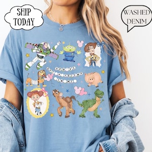 T-shirt featuring a graphic print of Toy Story characters including Buzz Lightyear, Woody, Jessie, Slinky Dog, Rex, Hamm, and an Alien. The text "YOU'VE GOT A FRIEND IN ME" is printed in the center.