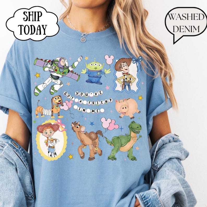 T-shirt featuring a graphic print of Toy Story characters including Buzz Lightyear, Woody, Jessie, Slinky Dog, Rex, Hamm, and an Alien. The text "YOU'VE GOT A FRIEND IN ME" is printed in the center.