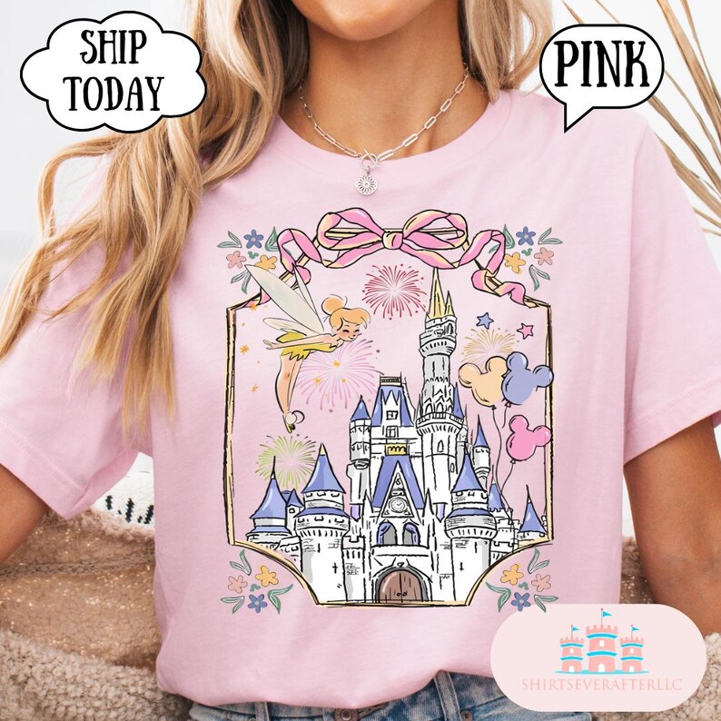 Puede incluir: Camiseta rosa claro con un castillo, un hada, fuegos artificiales y globos. El dise&ntilde;o est&aacute; enmarcado por un lazo rosa y detalles florales. La camiseta tiene los textos "PINK" y "SHIP TODAY" en bocadillos.