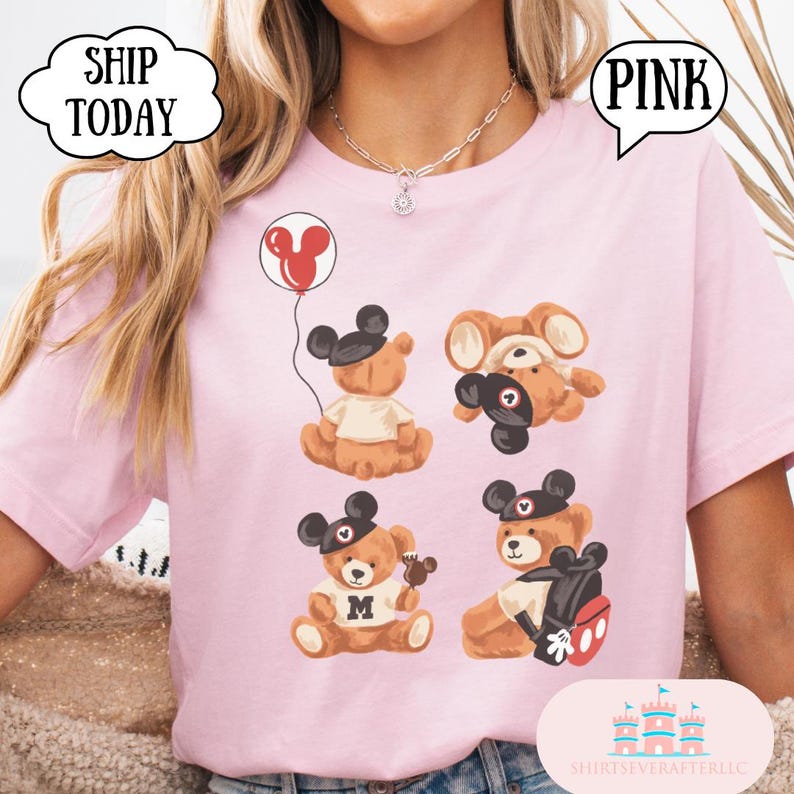 May include: A light pink t-shirt featuring a graphic print of four brown teddy bears wearing black mouse ear hats. One bear holds a red balloon, another is upside down, one wears a shirt with an M, and one carries a black backpack with red accents.
