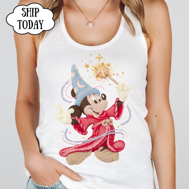 May include: White vest top with a graphic of Mickey Mouse as a sorcerer, holding a magic wand. Mickey is wearing a blue hat and a red robe. The text "SHIP TODAY" is in a cloud-shaped bubble.