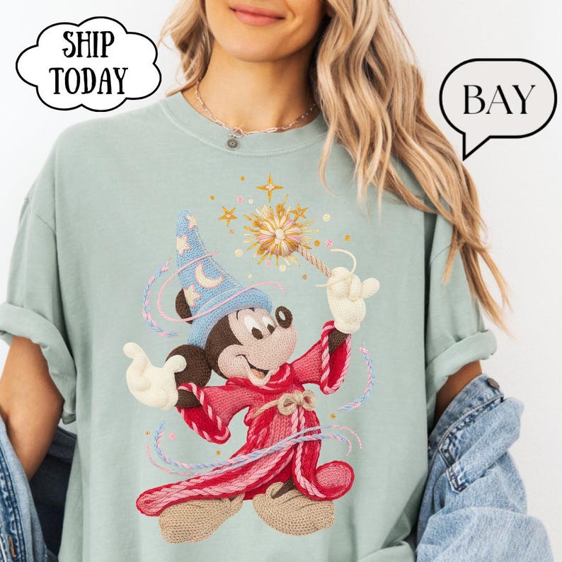 May include: A light green t-shirt featuring an embroidered Mickey Mouse dressed as a wizard, holding a wand with a starburst design. The shirt has the text "SHIP TODAY" in a cloud-shaped bubble.