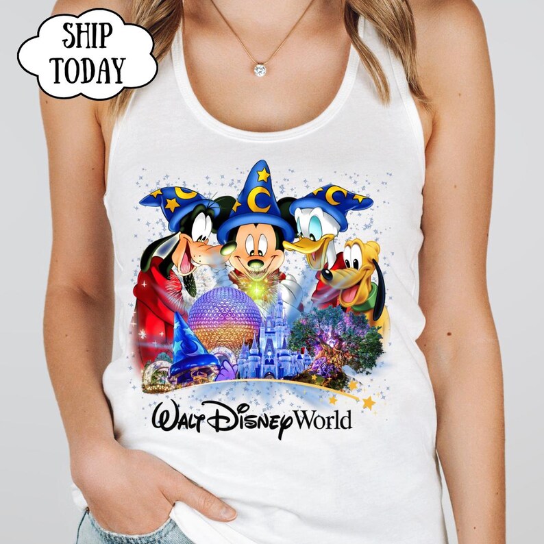 May include: White tank top featuring a colorful graphic of Mickey Mouse, Donald Duck, Goofy, and Pluto wearing wizard hats. The graphic includes the text "Walt Disney World" and a castle illustration.