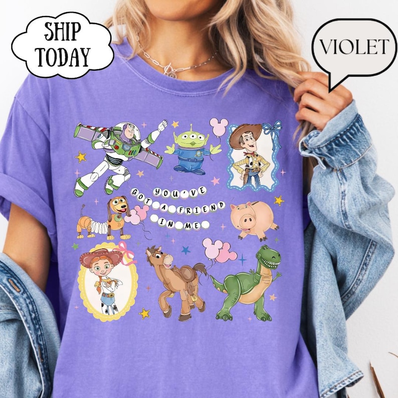 Puede incluir: Una camiseta violeta de manga corta con un estampado gr&aacute;fico de varios personajes animados, incluyendo un ranger espacial, un alien&iacute;gena verde, un vaquero, una vaquera, un perro, un cerdo, un caballo y un dinosaurio, con el texto "YOU'VE GOT A FRIEND IN ME".