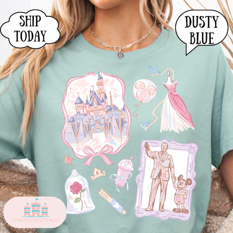 Op de afbeelding: Zachtblauwe t-shirt met een fantasie-thema grafische afbeelding met een kasteel, jurk en ballonnen. De t-shirt heeft ook de tekst "Ship Today" en "Dusty Blue".