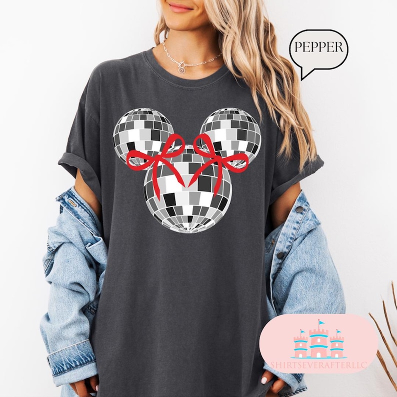 May include: A dark grey t-shirt with a black and white disco ball design featuring red bows. The text "PEPPER" is on a white speech bubble.