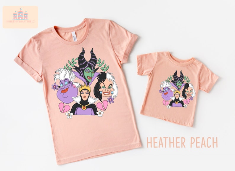 Puede incluir: Dos camisetas de color melocot&oacute;n con un estampado gr&aacute;fico de cuatro personajes de villanos de Disney: &Uacute;rsula, Mal&eacute;fica, la Reina Malvada y Cruella de Vil. El texto "HEATHER PEACH" est&aacute; impreso debajo de la camiseta m&aacute;s peque&ntilde;a.