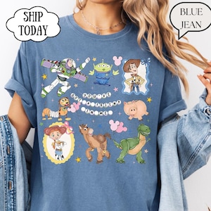 Puede incluir: Una camiseta azul con un estampado gr&aacute;fico de varios personajes animados, incluyendo un ranger espacial, un alien&iacute;gena verde, un vaquero, un perro salchicha, un cerdo, una vaquera, un caballo y un dinosaurio, con el texto "YOU'VE GOT A FRIEND IN ME".