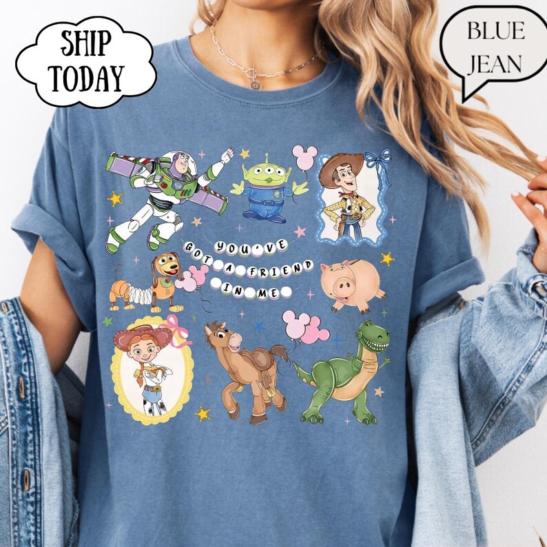 Puede incluir: Una camiseta azul con un estampado gr&aacute;fico de varios personajes animados, incluyendo un ranger espacial, un alien&iacute;gena verde, un vaquero, un perro salchicha, un cerdo, una vaquera, un caballo y un dinosaurio, con el texto "YOU'VE GOT A FRIEND IN ME".
