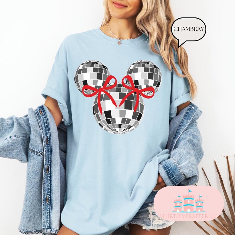 May include: A light blue t-shirt featuring a black and white disco ball design. The disco balls are shaped like Mickey Mouse ears with red bows.
