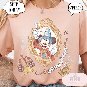 K&ouml;nnte beinhalten: Pfirsichfarbenes T-Shirt mit einem gerahmten Mickey Mouse mit Zaubererhut. Das Design enth&auml;lt das Wort "FANTASMIC" und andere Elemente zum Thema Fantasia. Das Shirt hat den Text "SHIP TODAY" in einer wolkenf&ouml;rmigen Blase.