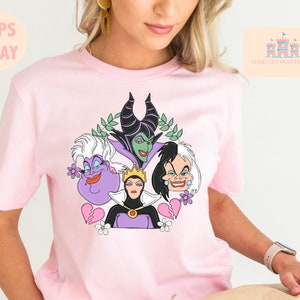 Puede incluir: Camiseta rosa con un gr&aacute;fico de cuatro personajes villanos de Disney: Mal&eacute;fica, &Uacute;rsula, Cruella de Vil y la Reina Malvada. Los personajes est&aacute;n rodeados de flores y corazones rotos.