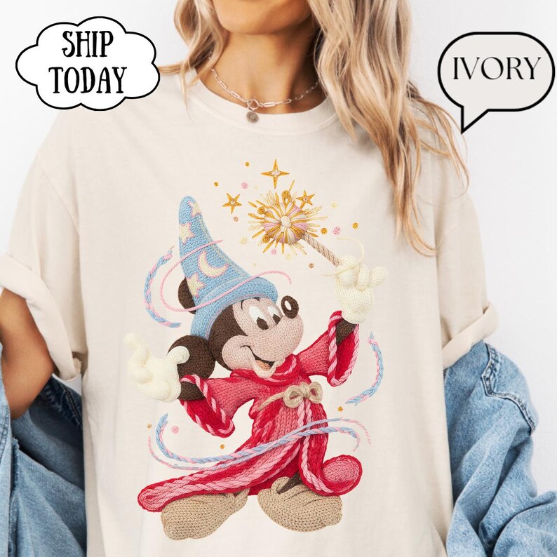 May include: Ivory t-shirt with a cartoon wizard character in a blue hat and red robe, holding a wand with a starburst design. The shirt has the text "SHIP TODAY" in a cloud-shaped speech bubble and "IVORY" in a speech bubble.