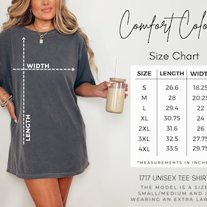 May include: A dark gray unisex tee shirt with the text "Comfort Colors" and a size chart. The chart shows measurements in inches for sizes S through 4XL. The model is wearing an extra large.