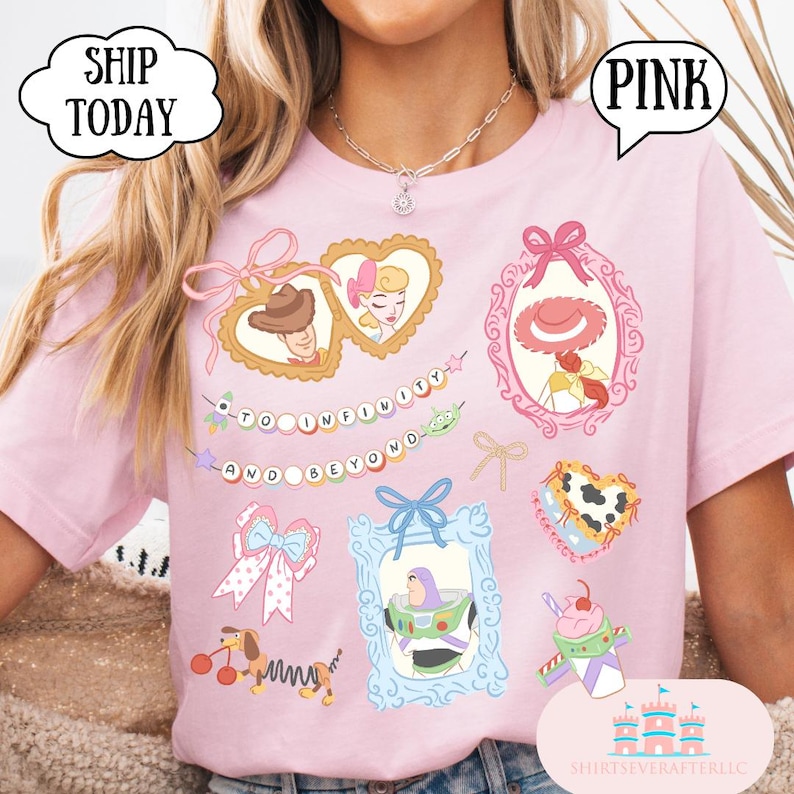 Op de afbeelding: Zachtroze T-shirt met illustraties van stripfiguren in sierlijke kaders. Het shirt bevat de zin "TO INFINITY AND BEYOND" en het woord "PINK" in een tekstballon. Het shirt heeft ook de tekst "SHIP TODAY" in een tekstballon.
