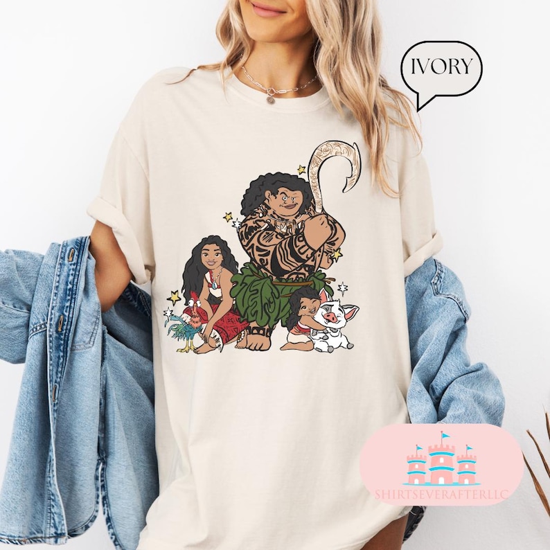 May include: Ivory t-shirt with a graphic print of Maui, Moana, Pua, and Hei Hei from the Disney movie Moana. The shirt is a light cream color and has a crew neck.