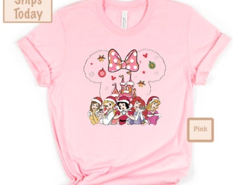 May include: Pink t-shirt with a Christmas-themed design featuring a cartoon image of Mickey Mouse's head with a bow, a castle, and five Disney princesses wearing Santa hats. The text "Pink" is visible in the lower right corner of the image.