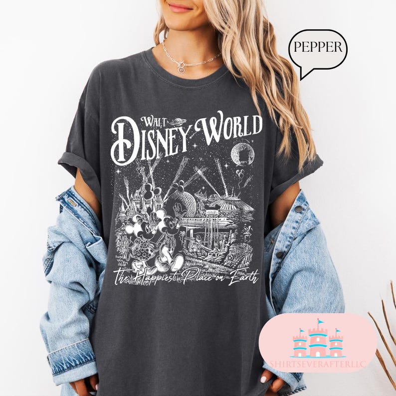 May include: Dark gray t-shirt featuring a Walt Disney World graphic. The design includes the words "Walt Disney World" in a stylized font, along with illustrations of iconic park elements and the phrase "The Happiest Place on Earth."