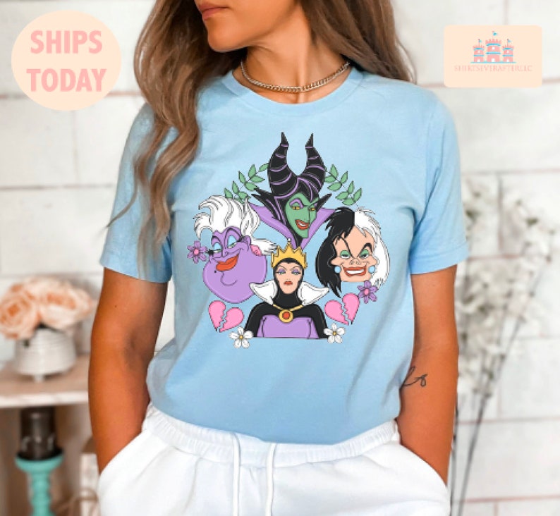 Puede incluir: Una camiseta azul claro con un estampado gr&aacute;fico de cuatro personajes villanos de Disney: Mal&eacute;fica, &Uacute;rsula, la Reina Malvada y Cruella de Vil. Los personajes est&aacute;n rodeados de flores y corazones rotos.
