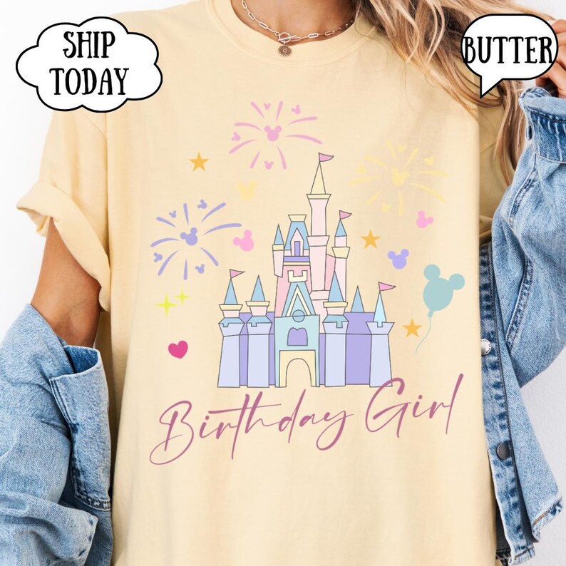 May include: A pale yellow t-shirt with a castle graphic, fireworks, stars, and a balloon. The text "Birthday Girl" is in cursive. The shirt has the word "Butter" in a speech bubble. The shirt is a light yellow color.