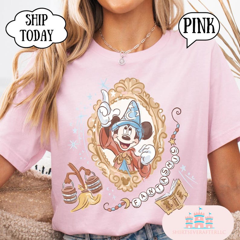 K&ouml;nnte beinhalten: Hellrosa T-Shirt mit einer gerahmten Illustration von Mickey Mouse in einem Zauberer-Outfit. Das Design enth&auml;lt das Wort "FANTASMIC" und andere magische Elemente. Das Shirt hat die Texte "PINK" und "SHIP TODAY" in Sprechblasen.