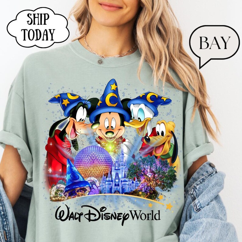 May include: A light green t-shirt featuring Mickey Mouse, Donald Duck, Goofy, and Pluto wearing wizard hats. The graphic includes a castle, a sphere, and the words "Walt Disney World".