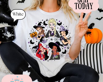 May include: White t-shirt with a graphic of five Disney princesses dressed as witches for Halloween. The princesses are Ariel, Tiana, Snow White, Elsa, and Belle. The graphic is surrounded by bats, stars, and spiderwebs.