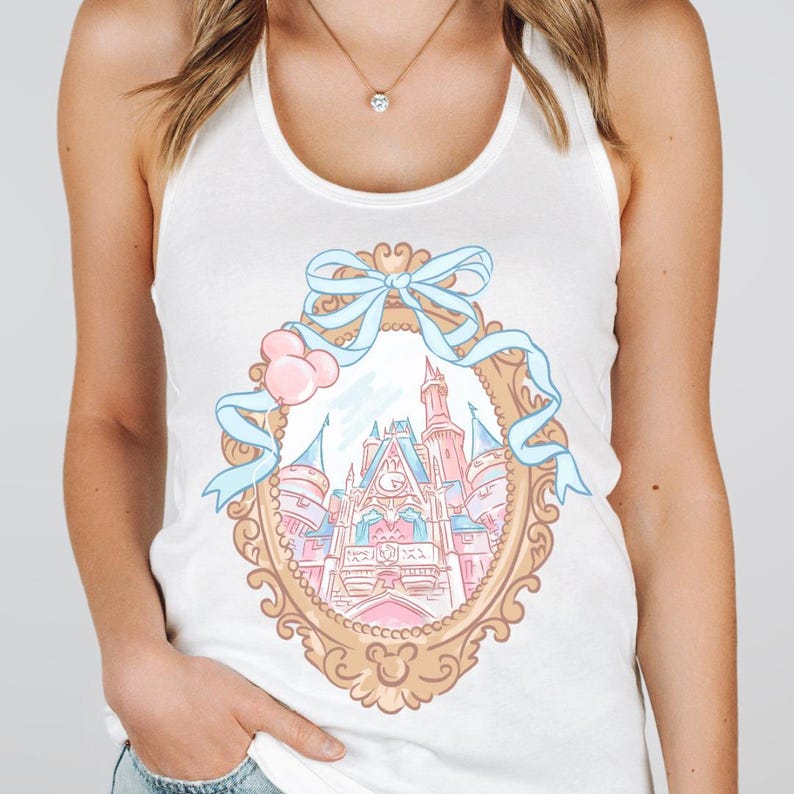Puede incluir: Camiseta sin mangas blanca con un dise&ntilde;o de castillo en tonos pastel dentro de un marco dorado, adornada con una cinta azul claro y globos rosas. El dise&ntilde;o incluye un castillo con detalles en rosa, azul y blanco, y una silueta de Mickey Mouse en la parte inferior.
