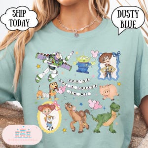 Puede incluir: Una camiseta azul polvoriento con un estampado gr&aacute;fico de los personajes de Toy Story, incluyendo a Buzz Lightyear, Woody, Jessie, Bullseye, Rex, Hamm, Slinky Dog y un Alien. El texto "YOU'VE GOT A FRIEND IN ME" aparece en el centro con estrellas.