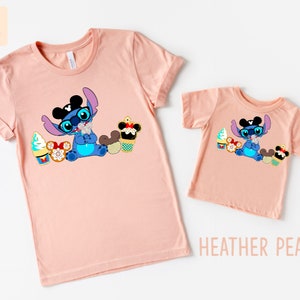 Puede incluir: Dos camisetas de color melocot&oacute;n con un personaje azul Stitch que lleva orejas de Mickey Mouse y gafas de sol. Stitch est&aacute; sosteniendo un helado de Mickey Mouse y rodeado de otras golosinas de Disney. El texto "HEATHER PEACH" est&aacute; impreso debajo de la camiseta m&aacute;s peque&ntilde;a.