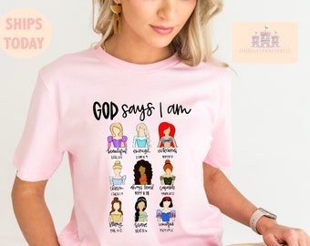 Può includere: Maglietta rosa con il testo "GOD says I am" e illustrazioni di principesse Disney con versetti biblici sotto ciascuna di esse.