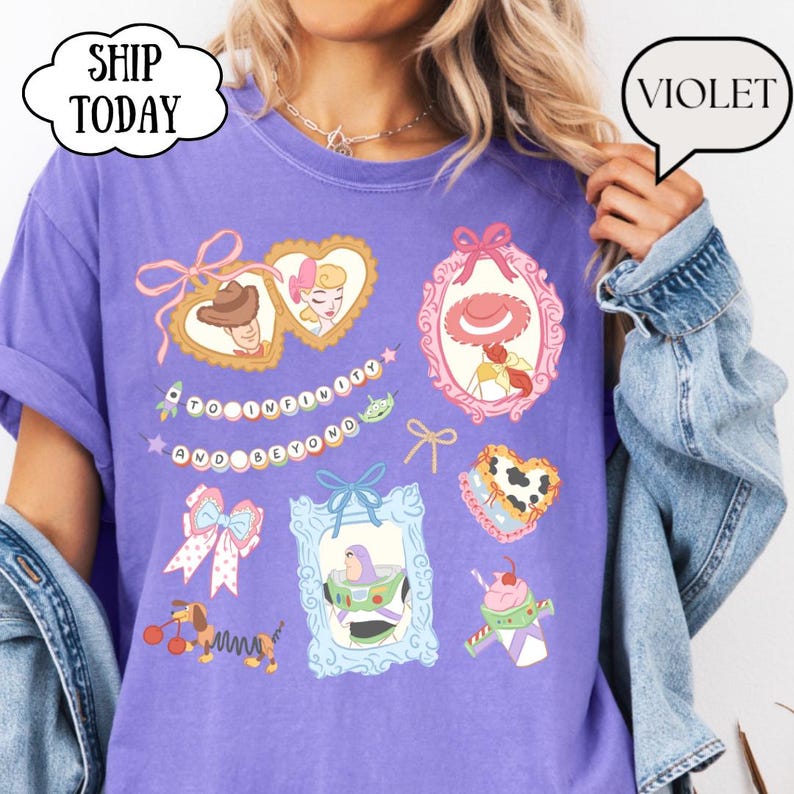 Op de afbeelding: Een paars T-shirt met illustraties van stripfiguren in sierlijke frames. Het shirt bevat de zin "TO INFINITY AND BEYOND" en een teckel met een veerkrachtig lichaam. Het woord "VIOLET" staat in een tekstballon.
