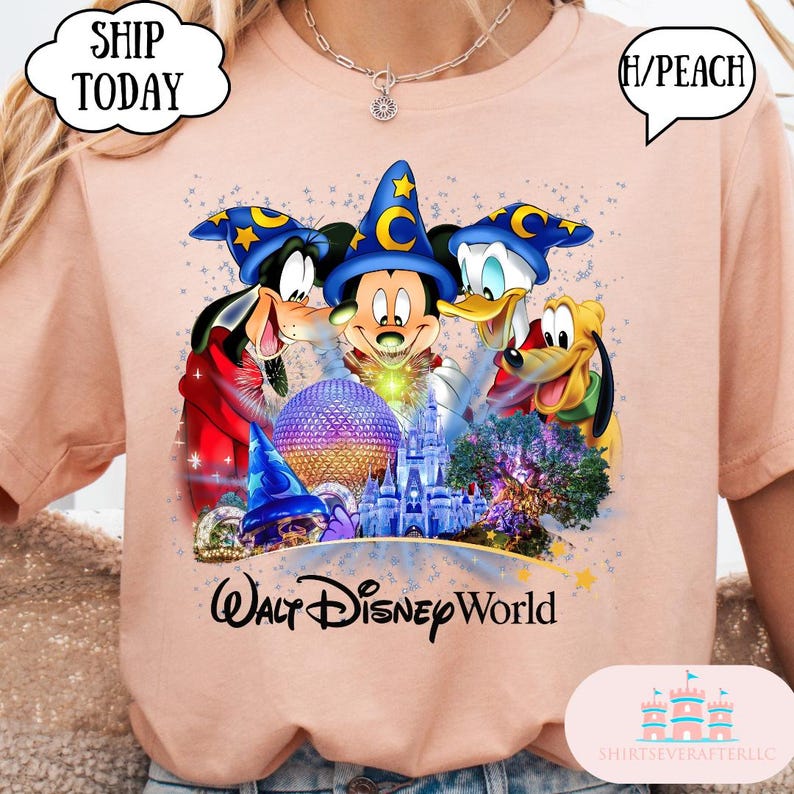 May include: Peach-colored t-shirt featuring a colorful graphic of Mickey Mouse, Goofy, Donald Duck, and Pluto in wizard hats, with a castle and the words "Walt Disney World." The shirt has a round neck.