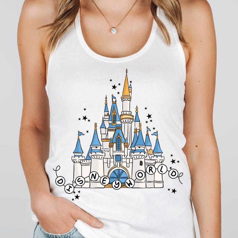 May include: White tank top featuring a colorful illustration of a fairytale castle with blue turrets and gold accents. The words "Disney World" are written in a circular design around the castle, with black stars scattered around the image.