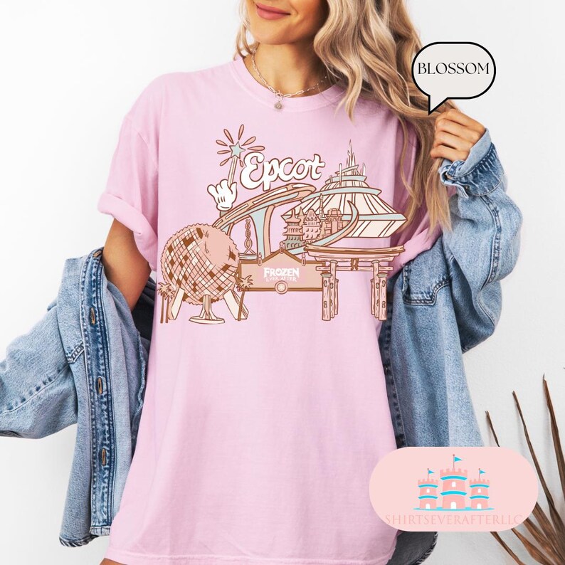 May include: Pink t-shirt featuring a graphic design of Epcot, including Spaceship Earth, the World Showcase, and the Frozen Ever After ride. The text "Epcot" is in a stylised font.