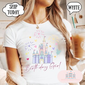 May include: White t-shirt featuring a castle graphic with fireworks and Mickey Mouse shapes. The words "Birthday Girl" are written in cursive. The shirt also has the text "SHIRTSEVERAFTERLLC".