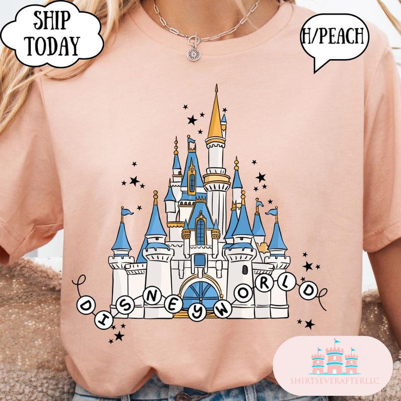 May include: A peach-colored t-shirt featuring a detailed illustration of a castle with blue and gold accents, and the words "DISNEY WORLD" in a circular design. The shirt has a crew neck and short sleeves.