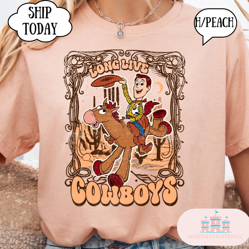 May include: Peach-colored t-shirt featuring a cartoon cowboy riding a horse, with the words "Long Live Cowboys" in a decorative frame. The design includes a cowboy with a hat and a desert landscape.