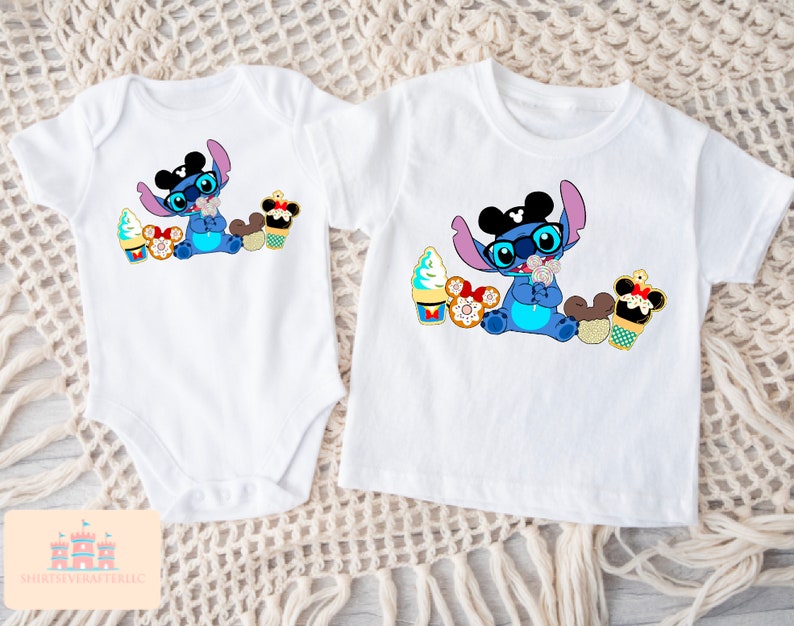 Puede incluir: Dos camisetas blancas con un personaje de dibujos animados azul que lleva orejas de Mickey Mouse y gafas de sol. El personaje sostiene un cono de helado de Mickey Mouse y est&aacute; rodeado de otras golosinas de Disney. Una camiseta es un body y la otra es una camiseta de manga corta.