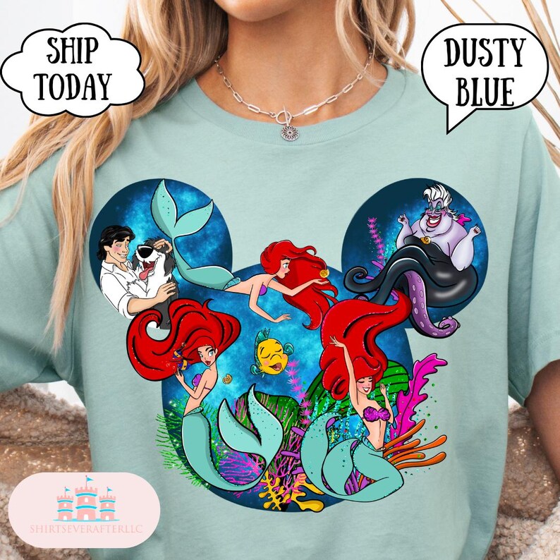 Puede incluir: Camiseta azul polvoriento con un dise&ntilde;o inspirado en Disney con Ariel y otros personajes de La Sirenita. El dise&ntilde;o incluye el texto "Dusty Blue" en una burbuja de di&aacute;logo. La camiseta tambi&eacute;n tiene el texto "Ship Today" en una burbuja de di&aacute;logo.